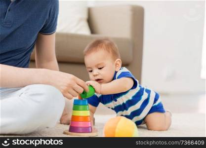 family, fatherhood and childhood concept - happy baby boy with father and toy pyramid at home. baby boy with father and pyramid toy at home