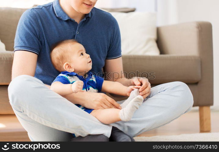 family, fatherhood and childhood concept - happy father with baby son sitting on floor at home. father with baby son sitting on floor at home