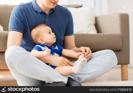 family, fatherhood and childhood concept - happy father with baby son sitting on floor at home. father with baby son sitting on floor at home