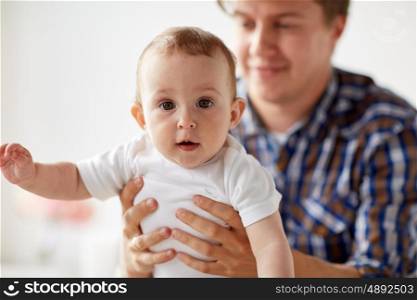 family, fatherhood and parenthood concept - close up of happy smiling young father with little baby at home