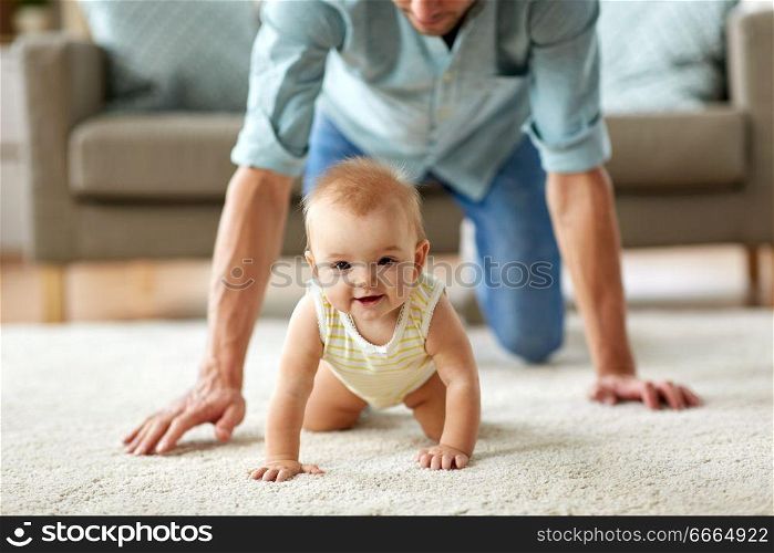family, fatherhood and parenthood concept - happy little baby girl with father at home crawling on floor. happy little baby girl with father at home