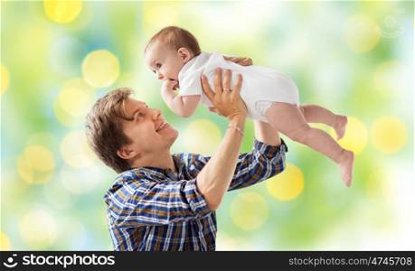 family, fatherhood and parenthood concept - happy smiling young father with little baby over green lights background