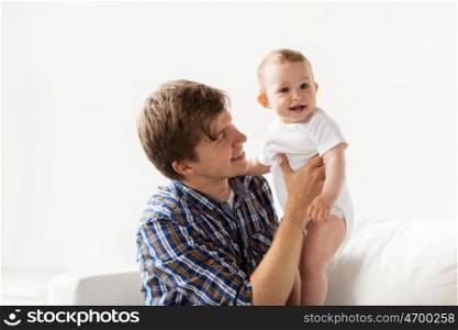 family, fatherhood and parenthood concept - happy smiling young father with little baby at home