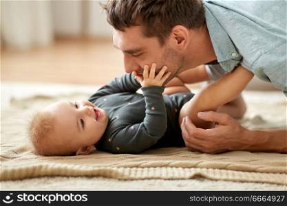 family, fatherhood and people concept - father playing with little baby daughter at home. father playing with little baby daughter at home