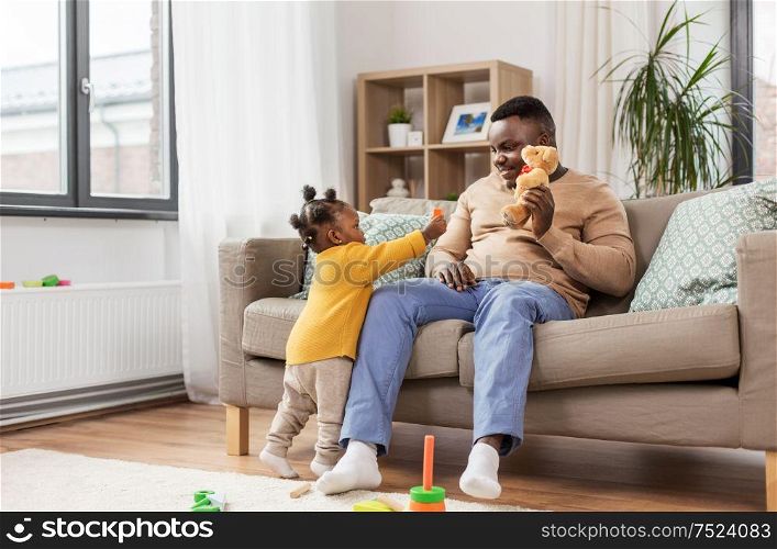 family, fatherhood and people concept - happy african american father playing with baby daughter at home. african american father playing with baby at home