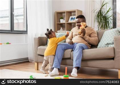 family, fatherhood and people concept - happy african american father playing with baby daughter at home. african american father playing with baby at home