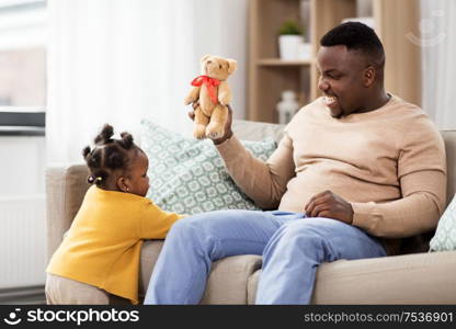 family, fatherhood and people concept - happy african american father playing with baby daughter at home. african american father playing with baby at home