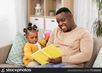 family, fatherhood and people concept - happy african american father reading book for baby daughter at home. african father reading book for baby daughter