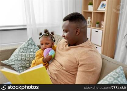 family, fatherhood and people concept - happy african american father reading book for baby daughter at home. african father reading book for baby daughter