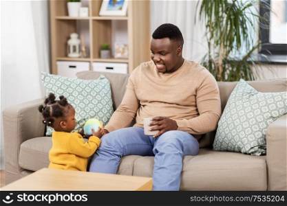family, fatherhood and people concept - happy african american father with baby daughter drinking coffee at home. happy african american father with baby at home