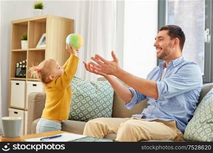 family, fatherhood and people concept - happy father and little baby daughter playing with ball at home. father and baby daughter playing with ball at home
