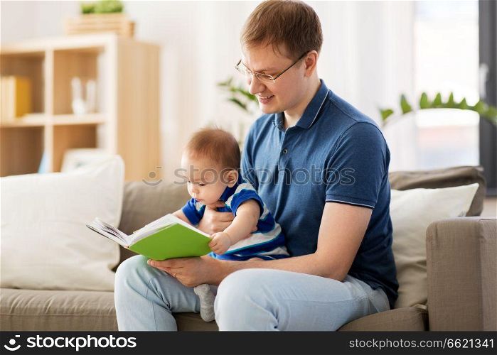 family, fatherhood and people concept - happy father and little baby son with book at home. happy father and little baby son with book at home