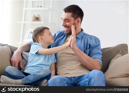 family, fatherhood and people concept - happy father and little son with tablet pc computer doing high five at home. father and son doing high five at home