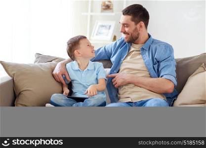 family, fatherhood and people concept - happy father and little son with tablet pc computer sitting on sofa at home. father and son with tablet pc at home