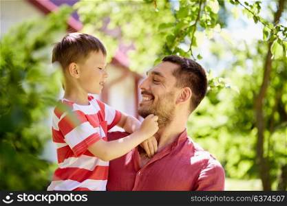 family, fatherhood and people concept - happy father and son at summer garden. happy father and son at summer garden