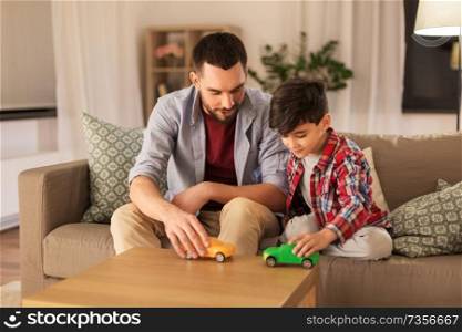 family, fatherhood and people concept - happy father and son playing with toy cars at home. father and son playing with toy cars at home