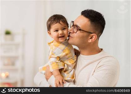 family, fatherhood and people concept - happy father kissing his little baby daughter at home. happy father kissing little baby daughter at home