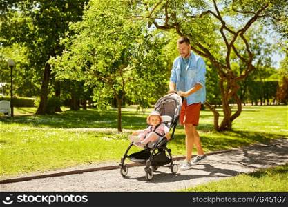 family, fatherhood and people concept - happy father with child in stroller walking at summer park. happy father with child in stroller at summer park