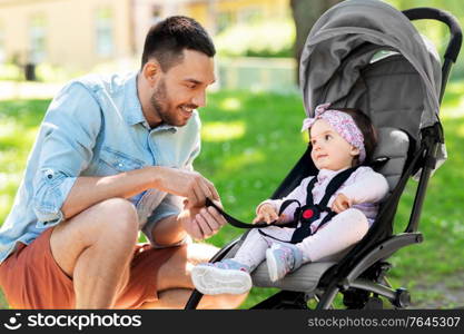 family, fatherhood and people concept - happy father with child or baby daughter in stroller at summer park. happy father with child in stroller at summer park