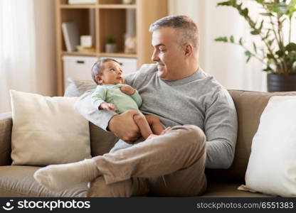 family, fatherhood and people concept - happy father with little baby boy sitting on sofa at home. happy father with little baby boy at home. happy father with little baby boy at home