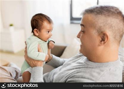 family, fatherhood and people concept - happy father with little baby boy sitting on sofa at home. happy father with little baby boy at home. happy father with little baby boy at home