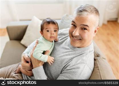 family, fatherhood and people concept - happy father with little baby boy sitting on sofa at home. happy father with little baby boy at home