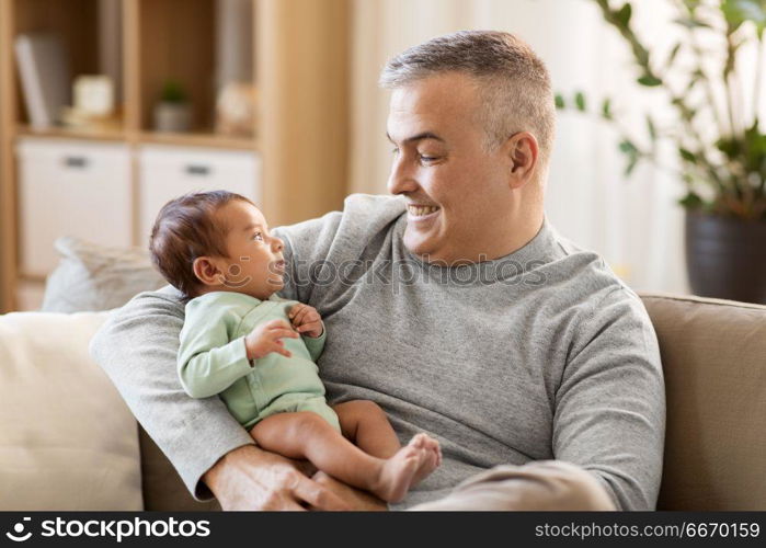 family, fatherhood and people concept - happy father with little baby boy sitting on sofa at home. happy father with little baby boy at home. happy father with little baby boy at home