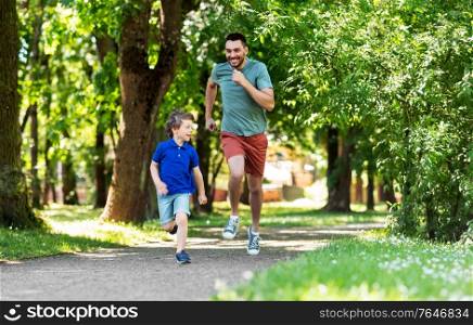 family, fatherhood and people concept - happy father with little son compete in running at summer park. happy father and son compete in running at park