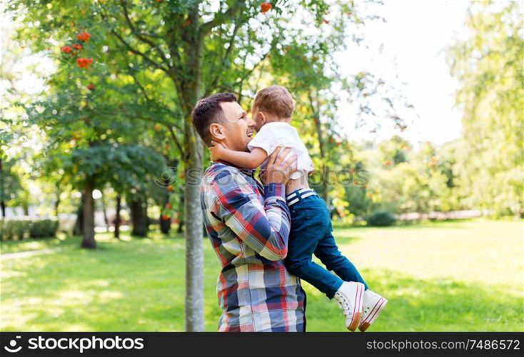 family, fatherhood and people concept - happy father with little son in summer park. happy father with little son in summer park