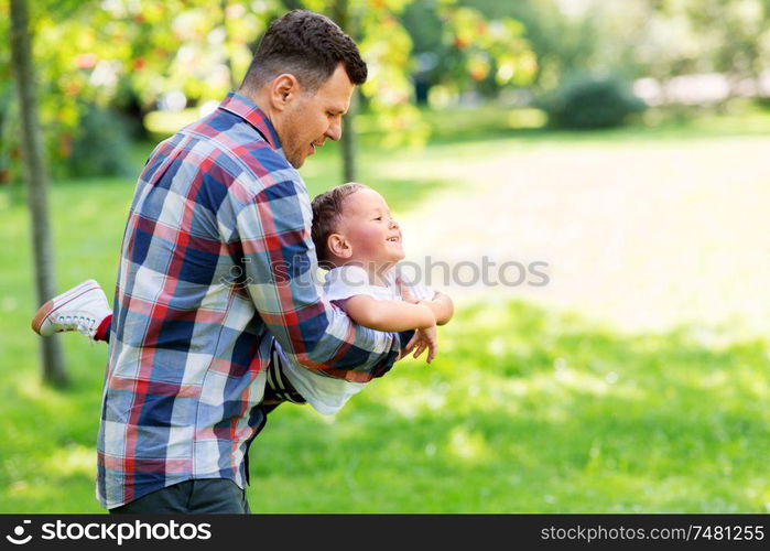 family, fatherhood and people concept - happy father with little son playing in summer park. happy father with son playing in summer park