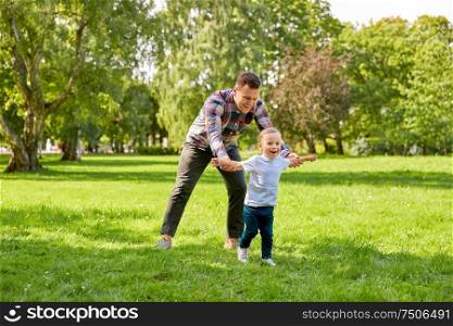 family, fatherhood and people concept - happy father with little son playing in summer park. happy father with son playing in summer park