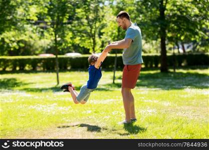 family, fatherhood and people concept - happy father with little son playing in summer park. happy father with son playing in summer park