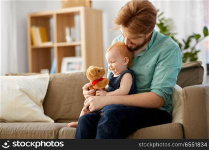 family, fatherhood and people concept - happy red haired father and little baby daughter playing with teddy bear at home. father and baby daughter with teddy bear at home. father and baby daughter with teddy bear at home