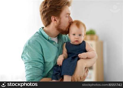 family, fatherhood and people concept - happy red haired father kissing his little baby daughter at home. happy father kissing his little baby daughter. happy father kissing his little baby daughter