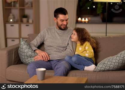 family, fatherhood and people concept - happy smiling father and little daughter at home at night. happy father and little daughter at home at night