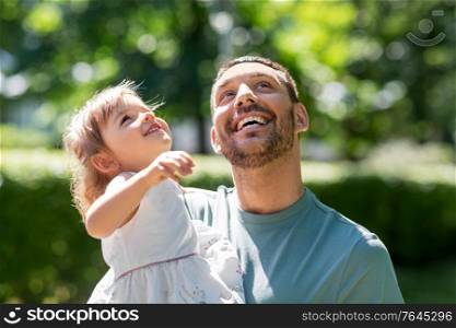 family, fatherhood and people concept - happy smiling father with baby daughter at summer park. happy father with baby daughter at summer park