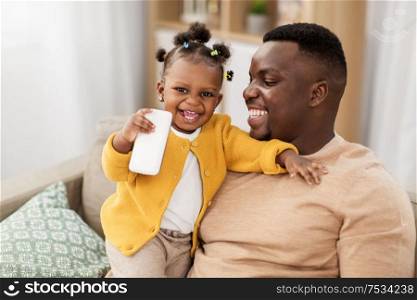 family, fatherhood and technology concept - african american father and little baby daughter with smartphone at home. father and baby daugter with smartphone at home