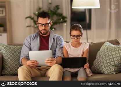 family, fatherhood and technology concept - father and daughter in glasses with tablet pc computers at home. father and daughter with tablet computers at home