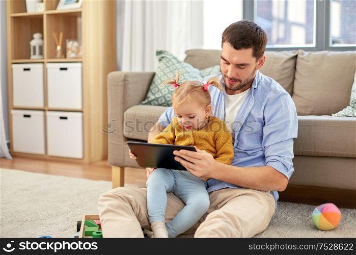 family, fatherhood and technology concept - happy father and baby daughter with tablet pc computer at home. father and baby daughter with tablet pc at home