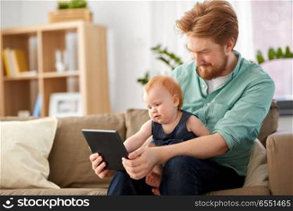 family, fatherhood and technology concept - happy red haired father and little baby daughter with tablet pc computer at home. father and baby daughter with tablet pc at home. father and baby daughter with tablet pc at home