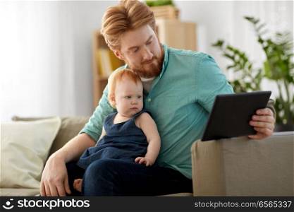 family, fatherhood and technology concept - happy red haired father and little baby daughter with tablet pc computer at home. father and baby daughter with tablet pc at home