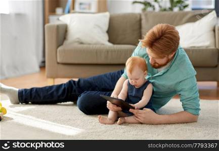 family, fatherhood and technology concept - happy red haired father and little baby daughter with tablet pc computer at home. father and baby daughter with tablet pc at home
