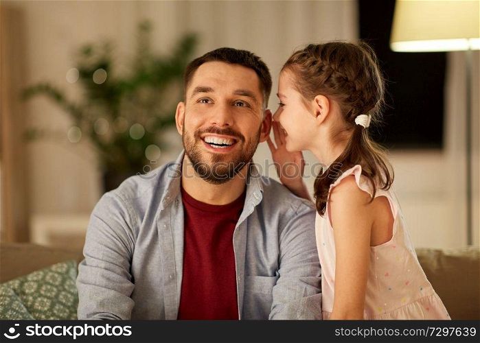 family, fatherhood, leisure and people concept - happy daughter whispering secret to father at home in evening. happy daughter whispering secret to father at home