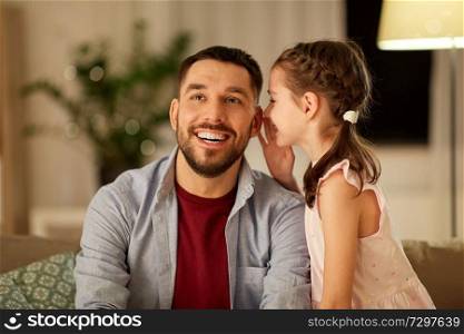 family, fatherhood, leisure and people concept - happy daughter whispering secret to father at home in evening. happy daughter whispering secret to father at home
