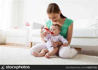 family, food, child, eating and parenthood concept - mother with puree and spoon feeding little baby at home