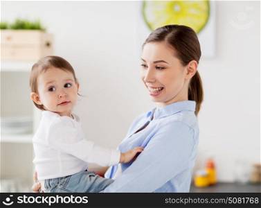 family, food, eating, motherhood and people concept - happy mother and little baby girl at home kitchen. happy mother and little baby girl at home kitchen