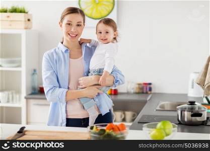 family, food, eating, motherhood and people concept- happy mother and little baby girl at home kitchen. happy mother and little baby girl at home kitchen