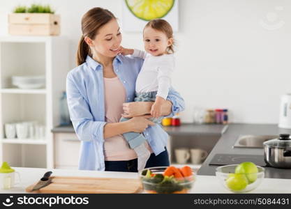 family, food, eating, motherhood and people concept- happy mother and little baby girl at home kitchen. happy mother and little baby girl at home kitchen. happy mother and little baby girl at home kitchen