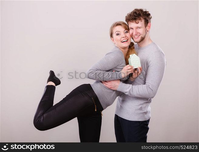 Family future youth household mortgage finances concept. Cheerful couple together with building model. Young girl with boy smiling presenting home symbol.. Cheerful couple together with building model