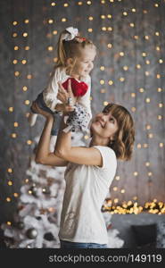 Family games-tossing the baby up.. Mother throws daughter on the background of sparkling lights 7191.